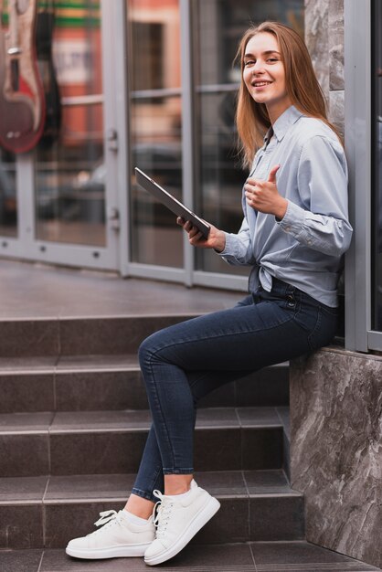 Lateral view blonde girl holding a tablet