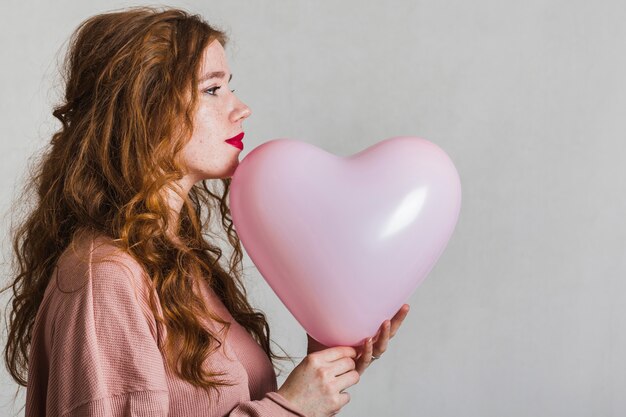 Free photo lateral view pretty woman holding a balloon