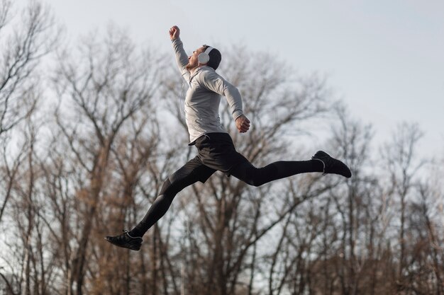 Lateral view sporty man jumping in forest