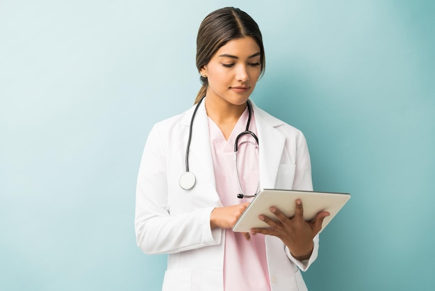 Latin female practitioner using digital tablet over isolated colored background