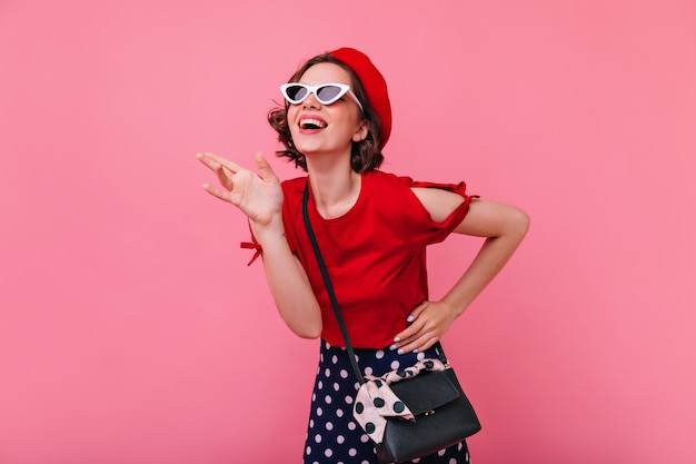 Laughing carefree girl with short haircut posing. Emotional french white woman in beret smiling.