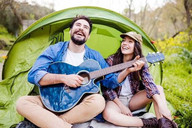 Laughing couple playing guitar