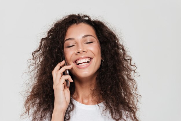 Laughing curly woman which talking by the smartphone