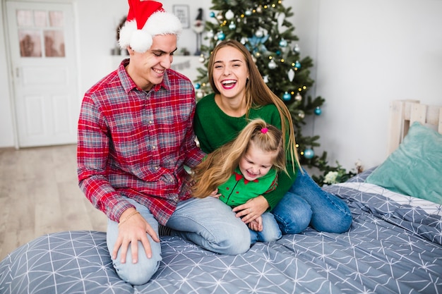 Laughing family on bed at christmas