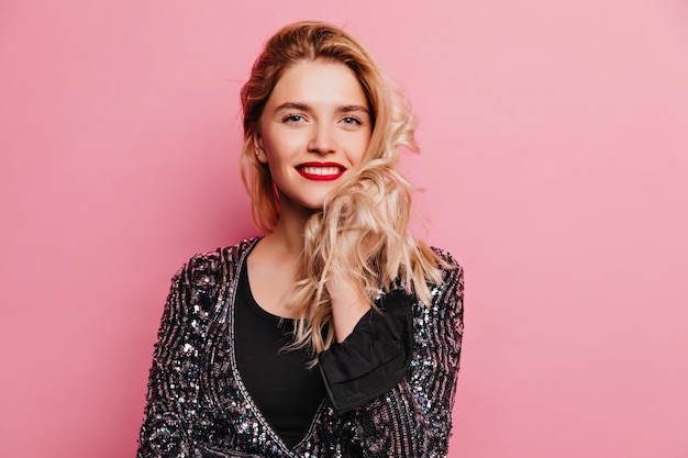 Laughing fascinating girl expressing happiness. Indoor photo of fashionable blonde lady standing on pink wall.