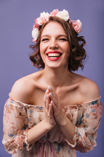 Laughing fashionable girl posing in romantic dress. Fascinating curly female model in circlet of flowers expressing positive emotions.