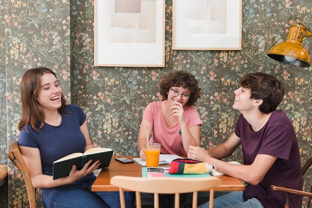 Laughing teenagers studying in cafe