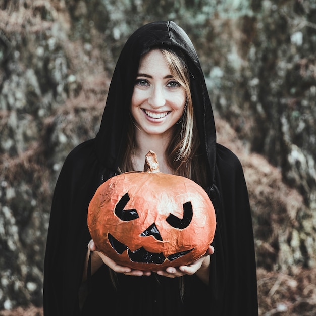 Laughing woman holding pumpkin in park