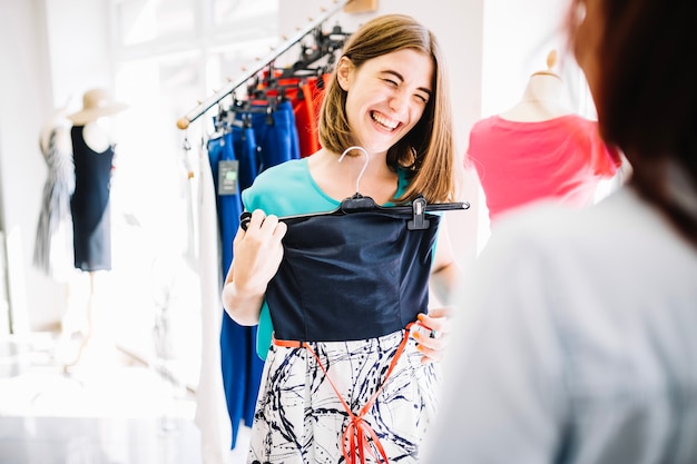 Laughing woman showing dress to her friend