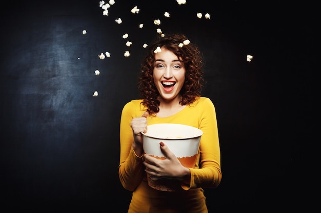 Free photo laughing woman throwing up popcorn up in the air