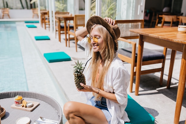 Free Photo laughing woman in yellow sunglasses drinking fruit cocktail and sunbathing.