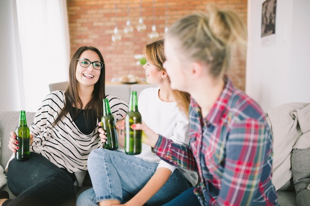 Laughing women relaxing with beer at home