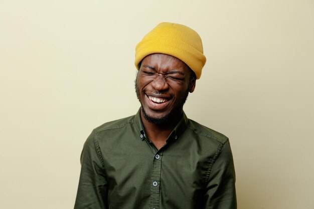 laughing young african american male in hat wearing green shirt isoloated on white background