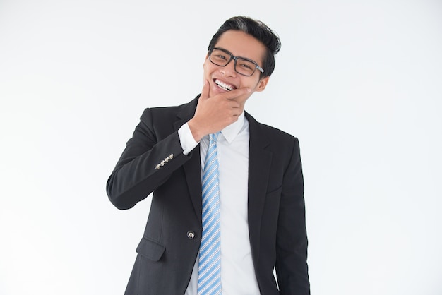 Laughing young Asian businessman touching chin