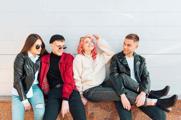 Free photo laughing young and attractive friends sitting on bench