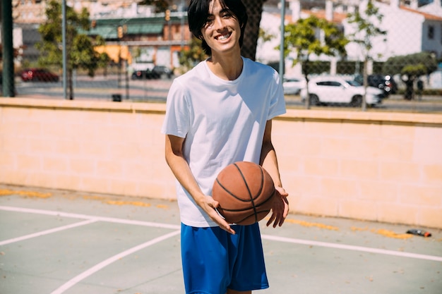 Free photo laughing young man with basketball looking at camera