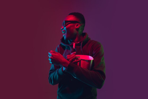 Laughting Africanamerican mans portrait on gradient studio in neon light