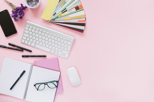 Lavender; cellphone; keyboard and mouse with office stationery on colored pink background