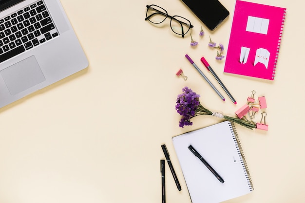 Lavender flower bunch with stationeries and laptop on beige background