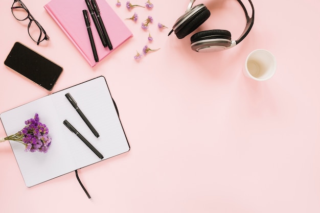 Lavender flowers with office stationery and cellphone on pink background