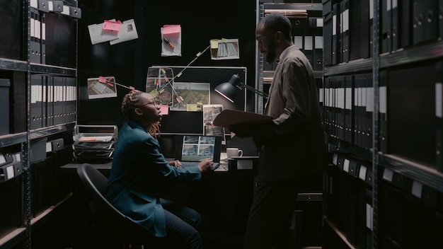 Free photo law agents team analyzing private records in evidence room, conducting criminal investigation in archive space office. professional detectives analyzing case files report, forensic evidence.