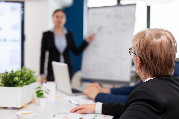 Free photo leader making sales report for top company managers drawing charts on white board. serious speaker boss executive, business trainer explaining development strategy to motivated mixed race employees.