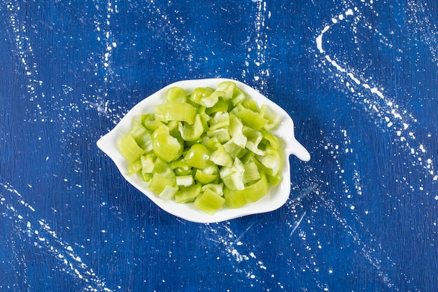 Leaf-shaped plate of sliced green bell peppers on marble surface. 