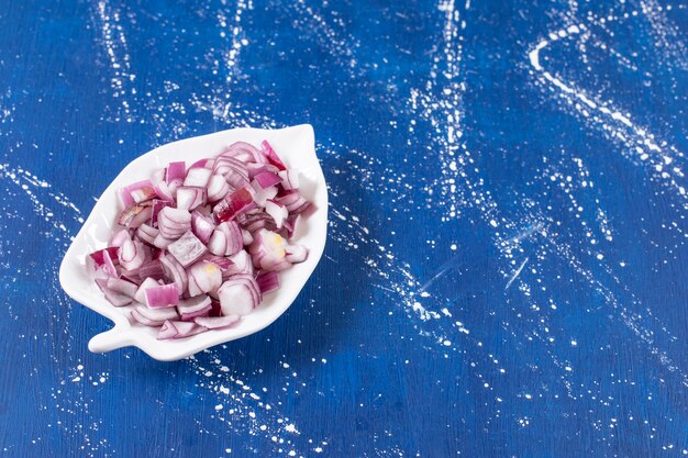 Leaf-shaped plate of sliced purple onions on marble surface