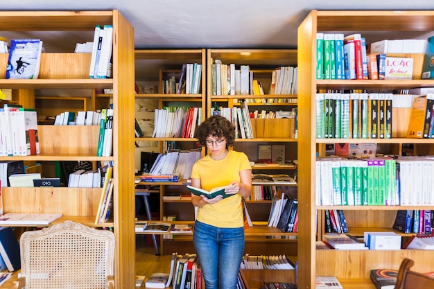 Learning lady standing between bookcases