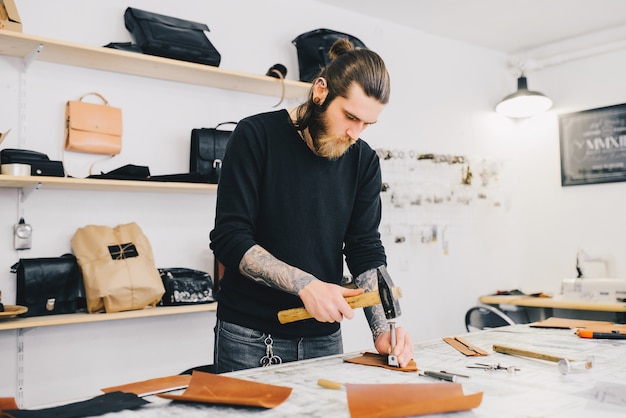 Leather craftsman working with leather using hammer. 