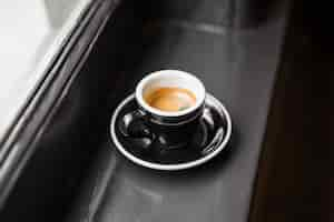 Free photo leftover coffee in black cup on window sill