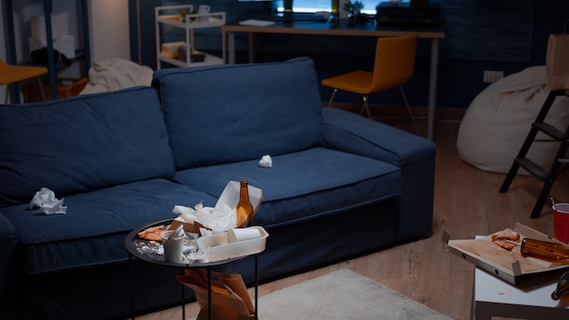 Free photo leftover of pizza empty beer bottles and napkins on table in messy living room