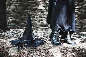 Free photo legs of woman in black dress with hat on ground