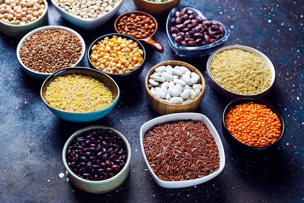 Free photo legumes and beans assortment in different bowls on light stone background . top view. healthy vegan protein food.