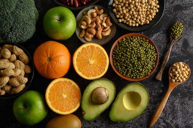 Legumes and fruit on a black cement floor surface.