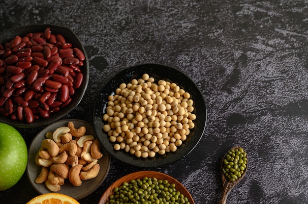 Legumes and fruit on a black cement floor surface.