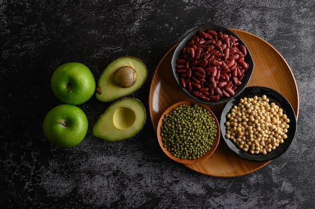 Legumes and fruit on a black cement floor.