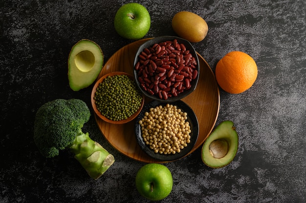 Legumes and fruit on a black cement floor.