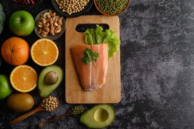 Free Photo legumes, fruit, and salmon fish pieces on a wooden chopping board.