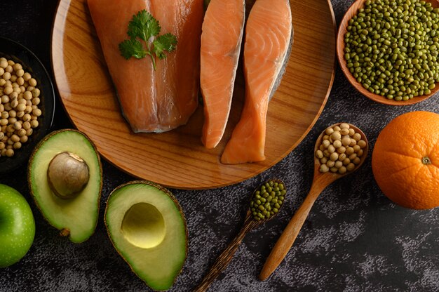 Free Photo legumes, fruit and salmon pieces on a wooden plate.