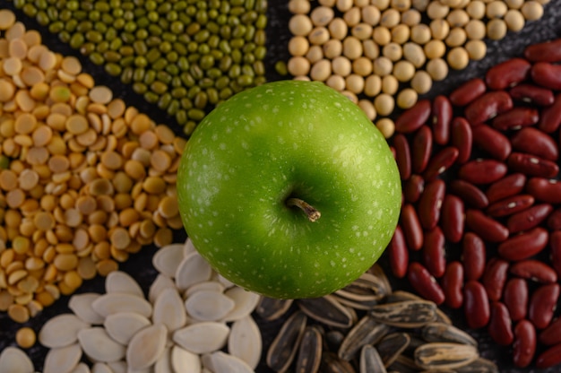 Free photo legumes with apple on a black cement floor surface.