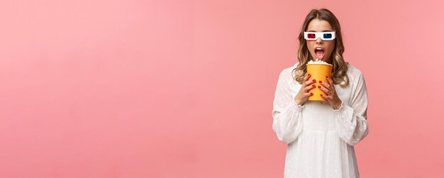 Free photo leisure goingout and spring concept portrait of cute blond funny girl in cinema eating popcorn from