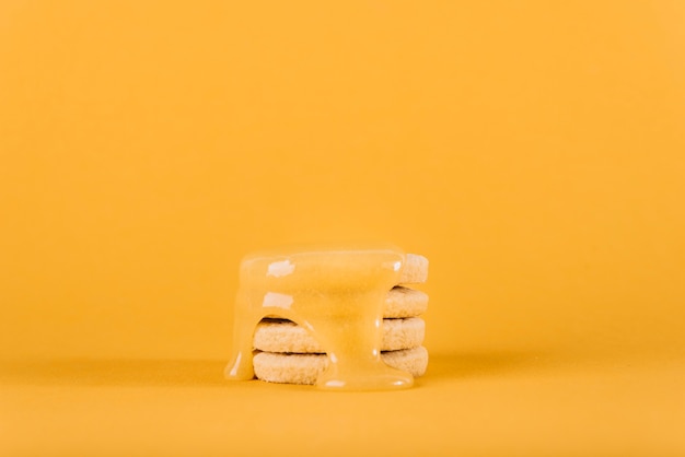 Free Photo lemon curd dripping over stack of cookies on yellow backdrop