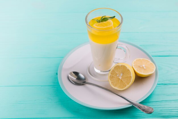 Lemon mousse in glass on plate over turquoise backdrop