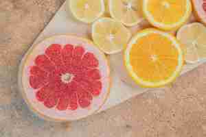 Free photo lemon, orange and grapefruit slices on wooden board.