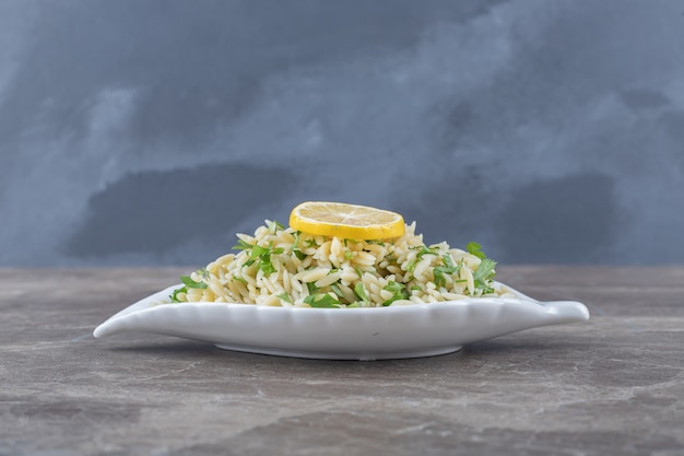 Lemon slice on pasta with green vegetables , on the marble surface.