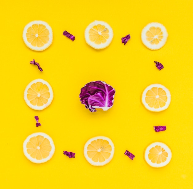 Free photo lemon slices frame with purple cabbage in the center over yellow background