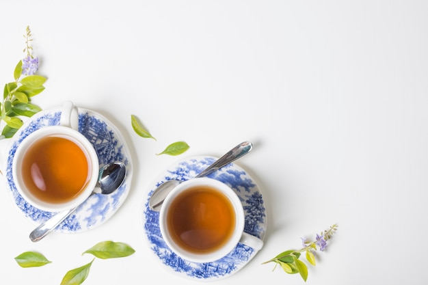 Lemon tea herbal leaves with cup and saucer against white backdrop