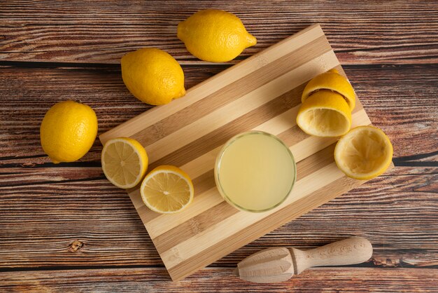 Lemonade in a glass cup on the wooden board, top view