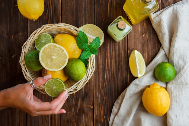 Free Photo lemons in a basket with white cloth hand holding half of lemon top view on a wooden surface